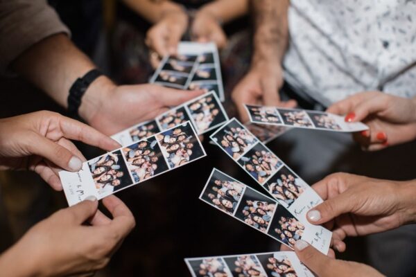Hands holding photo booth strips at a Toronto holiday event, showcasing custom prints and candid group shots.