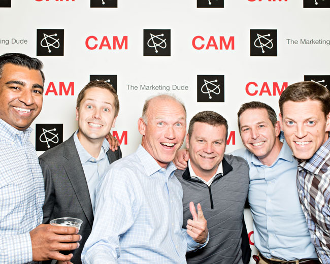 Group of colleagues smiling in front of a branded step-and-repeat backdrop at a Richmond Hill corporate photo booth activation